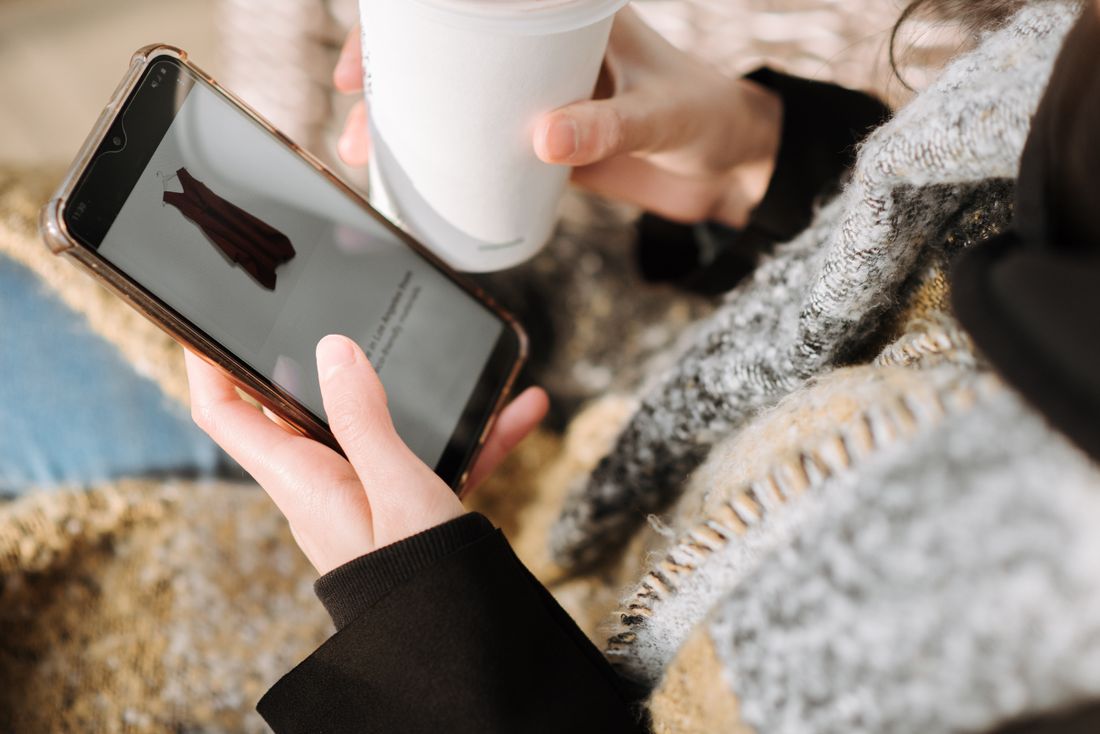Femme choisissant un vêtement sur son smartphone lors d'un achat en ligne