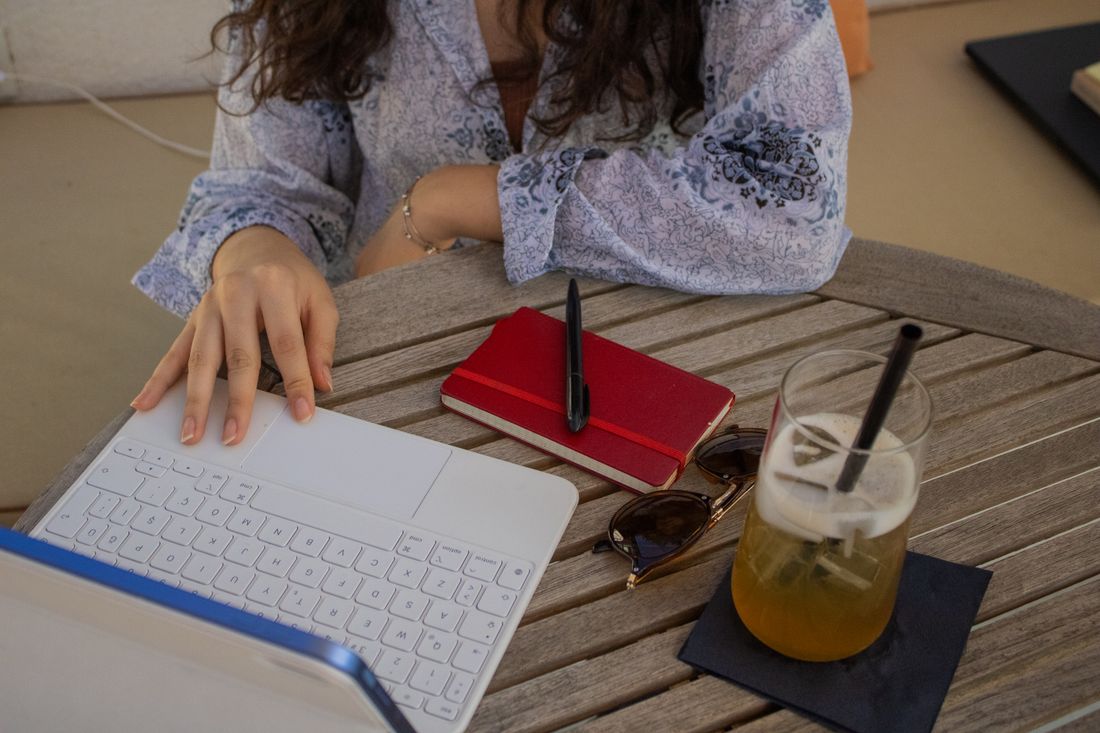 Femme lisant du contenu lifestyle sur ordinateur en terrasse de café