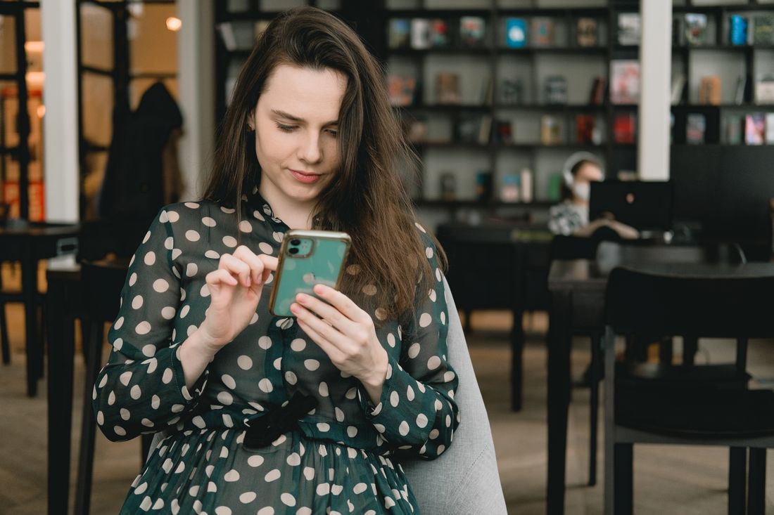 Femme consultant du contenu sur son smartphone dans une bibliothèque