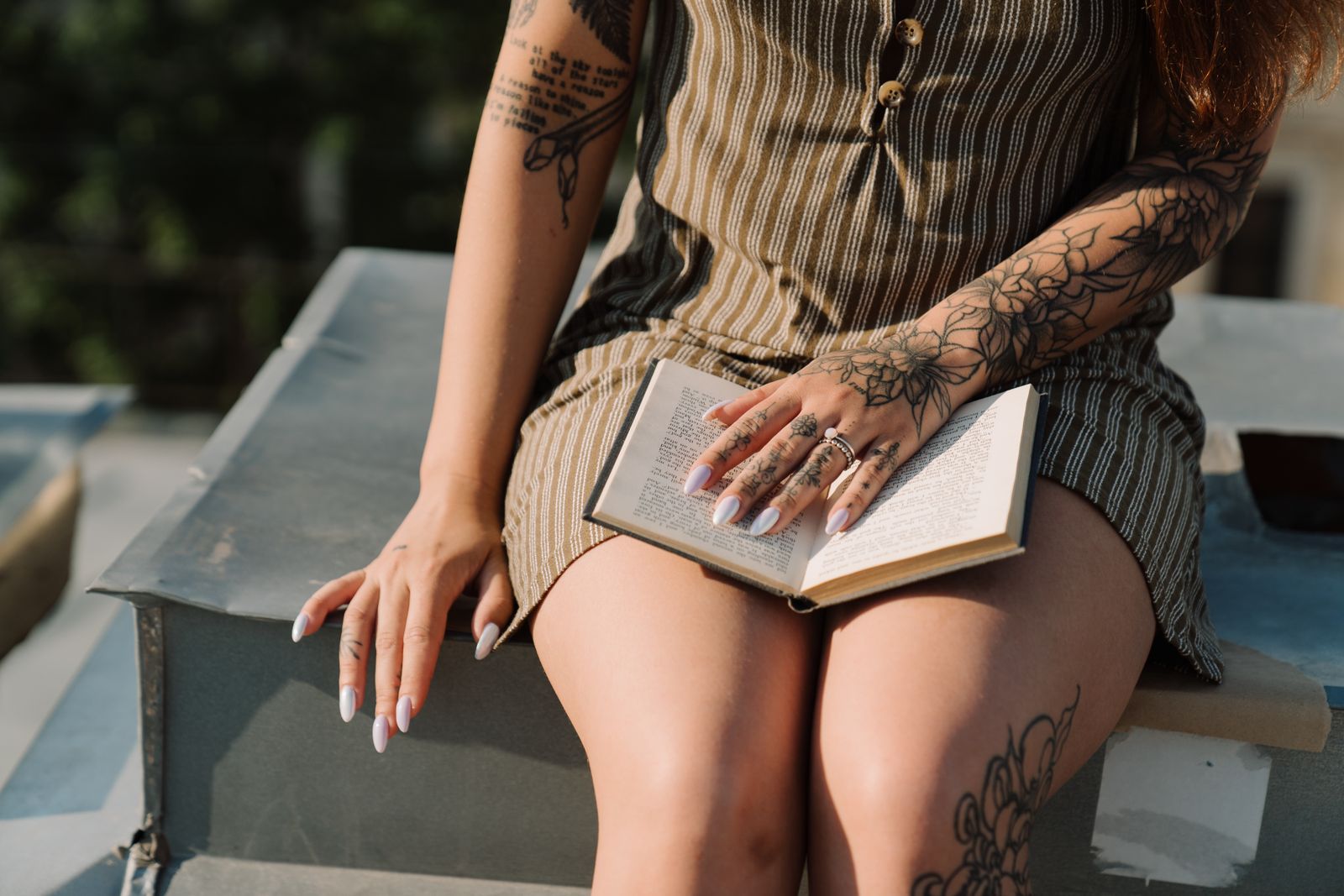 Femme tatouée qui lit un livre au soleil