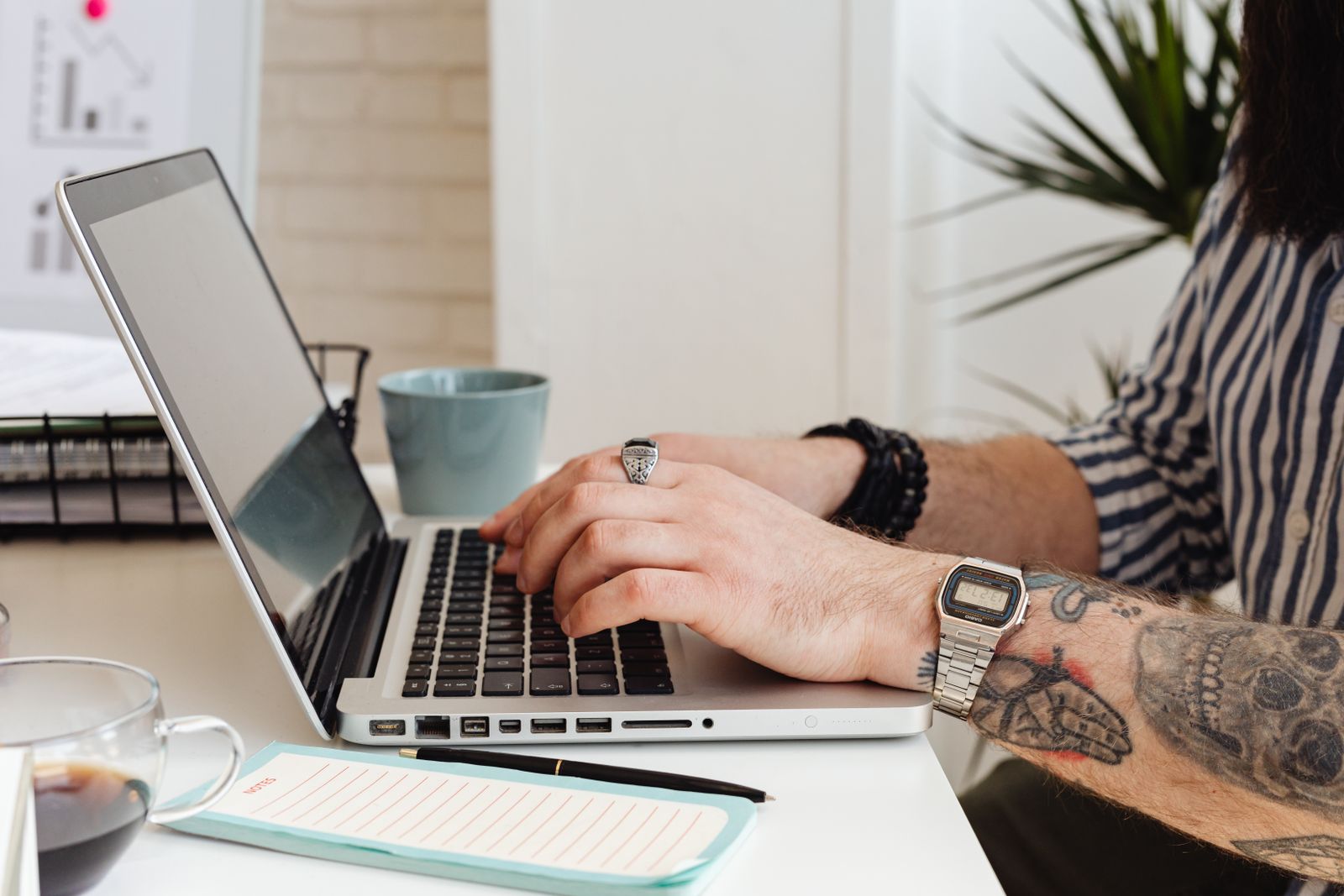 Personne tatouée travaillant sur un ordinateur portable